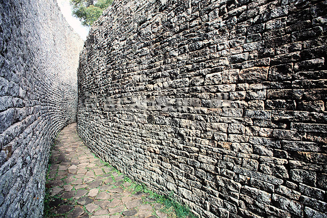 Great Zimbabwe. Great Zimbabwe - Great Enclosure - Parallel Passage mellem inder- og ydermur - Ordet Zimbabwe betyder stenhus p� shona. ( Scan af KOL3605 ) ; ; Great Zimbabwe / Masvingo; Zimbabwe; Afrika; ; Zimbabwe er opkaldt efter ruinerne