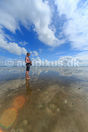 R�m�. Ung pige (model release OK) p� vaden ved S�nderstrand - himmel og skyer spejler sig i det spejlblanke lave vand i vadehavet; ; R�m�; Danmark; ; ; 